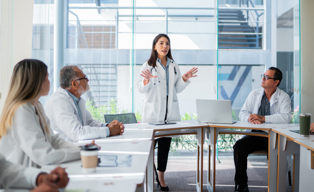 Physicians in a tumor board meeting, one presenting
